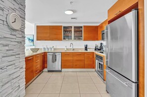 A modern kitchen with wooden cabinets, a stainless steel refrigerator, and a built-in oven. - Midtown Miami Gem Wynwood W/ Huge Terrace Free Parking (Miami)