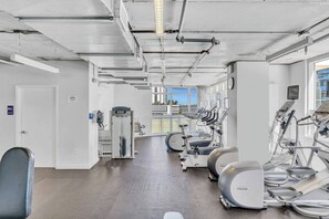 A gym with cardio machines, weight equipment, and a view of the outside. - Midtown Miami Gem Wynwood W/ Huge Terrace Free Parking (Miami)