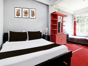 A hotel room with a bed, a red cabinet, a window with curtains, and framed artwork on the wall. - Super Hotel O Ghoom Aps Homestay (Darjeeling)