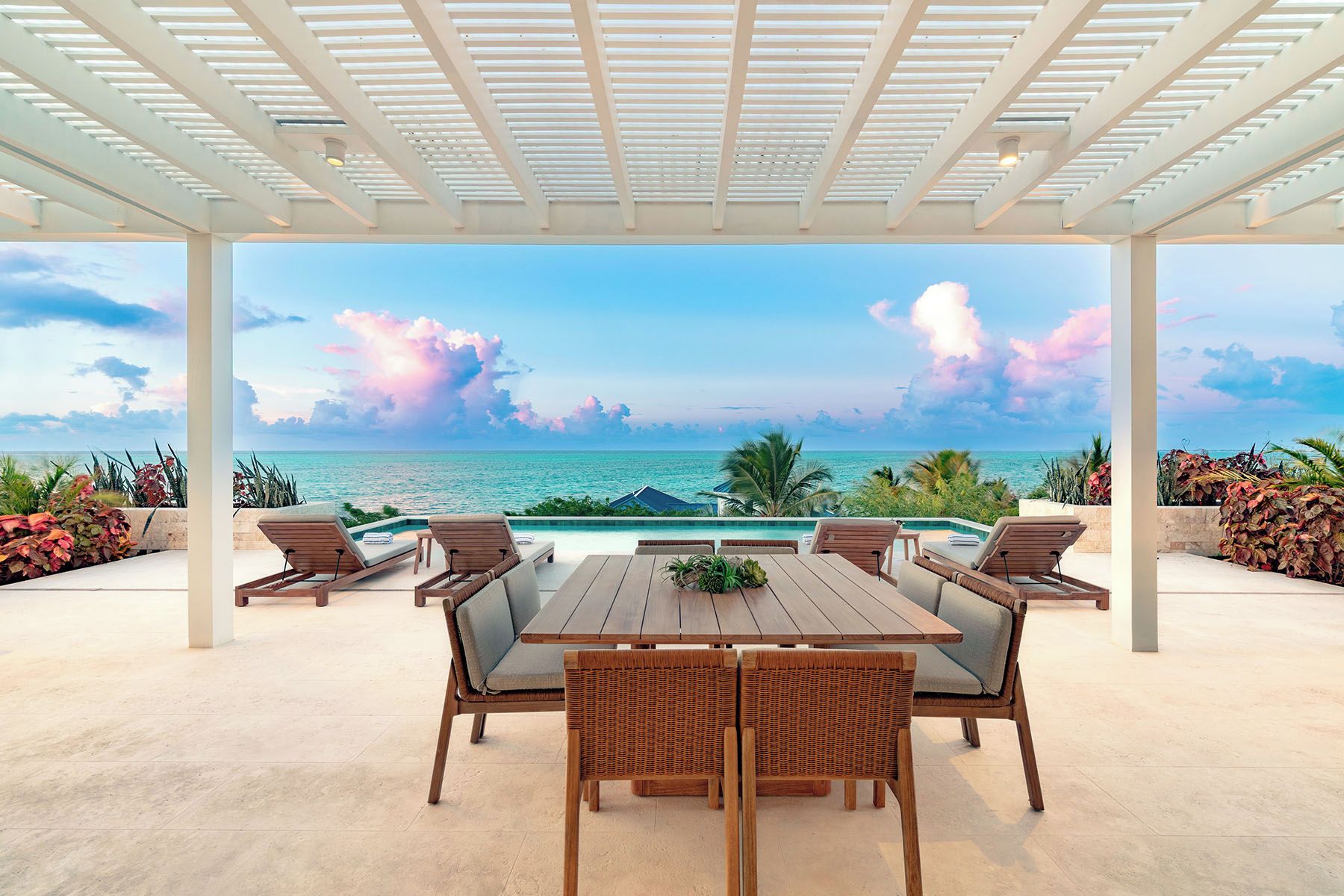 Un patio exterior con piscina, sillas de descanso y una mesa.