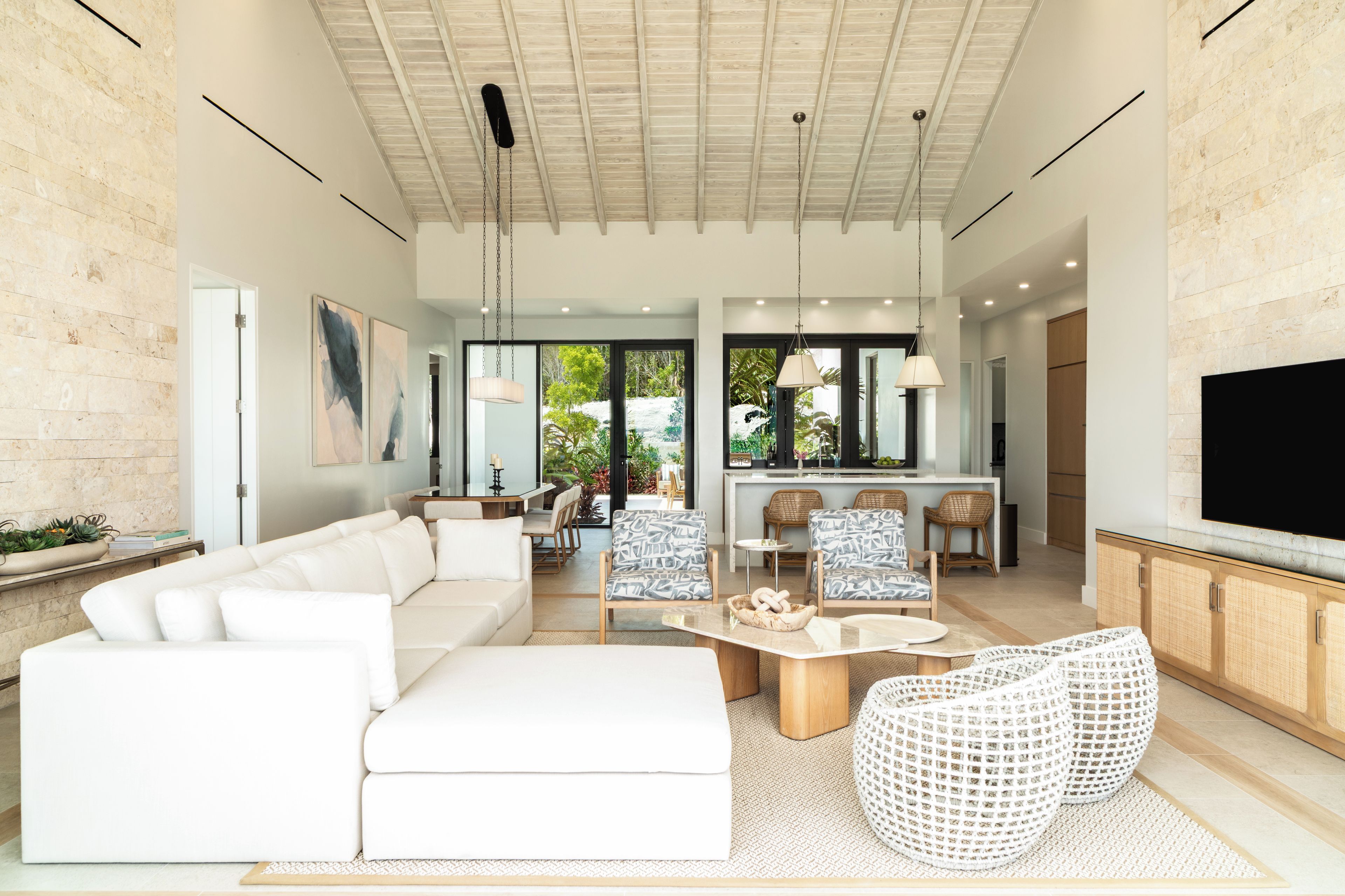 A spacious living area with a white sofa, a coffee table, and a TV mounted on the wall.