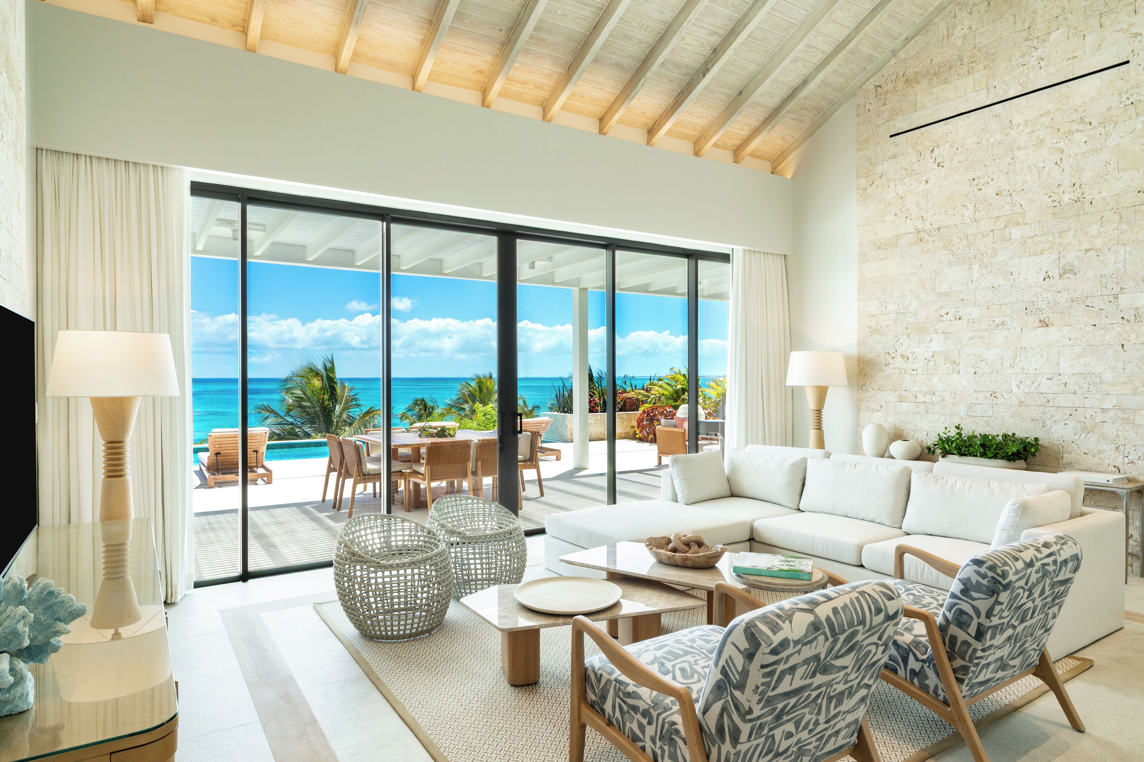 A spacious living room with a large sliding glass door leading to a balcony with a view of the ocean.