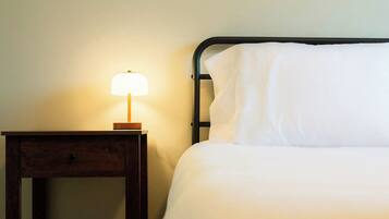 A bed with white bedding and a nightstand with a lamp.