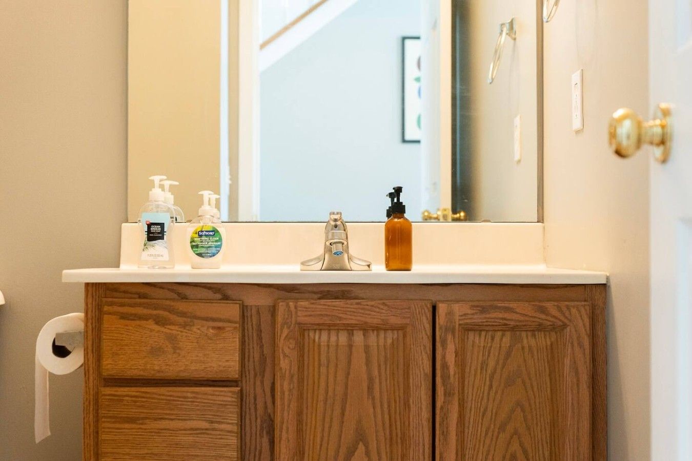 Une salle de bain avec un meuble-lavabo en bois, un miroir et des articles de toilette posés sur le comptoir.