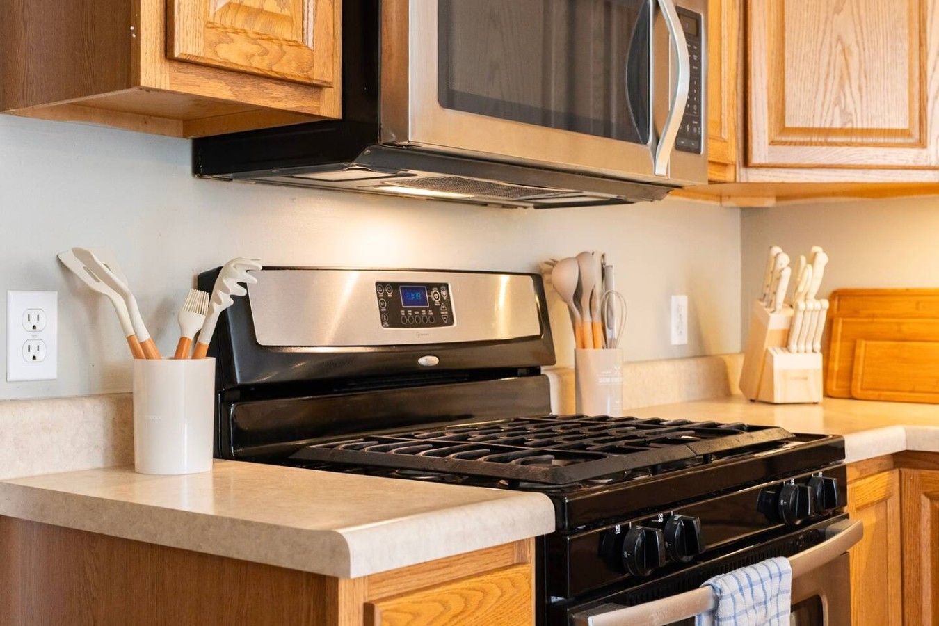 Una cocina con extractor de acero inoxidable, un microondas sobre la estufa y armarios de madera.