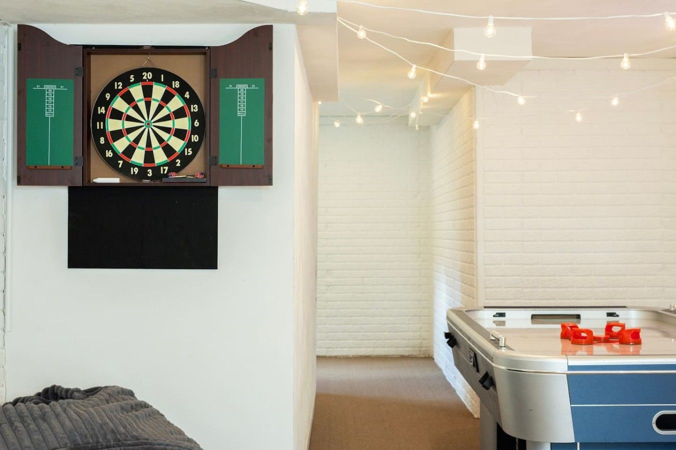 Una habitación con dardos, un televisor de pantalla plana y una mesa de fútbolín.