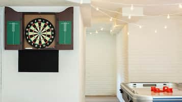 Una habitación con dardos, un televisor de pantalla plana y una mesa de fútbolín.
