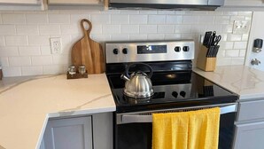 Una cocina con estufa, microondas y hervidor sobre la encimera.