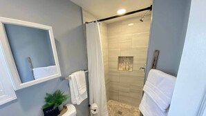 Un baño moderno con ducha, inodoro y una pequeña zona de lavamanos.
