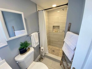 A modern bathroom with a shower, toilet, and a small sink area. - Downtown Living: Walk to Eats, Drinks & History (Frederick)