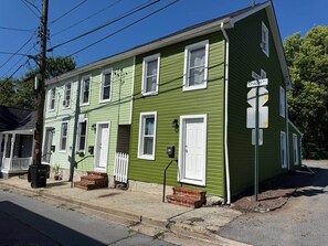 A two-story building with a green exterior and white trim. - Downtown Living: Walk to Eats, Drinks & History (Frederick)