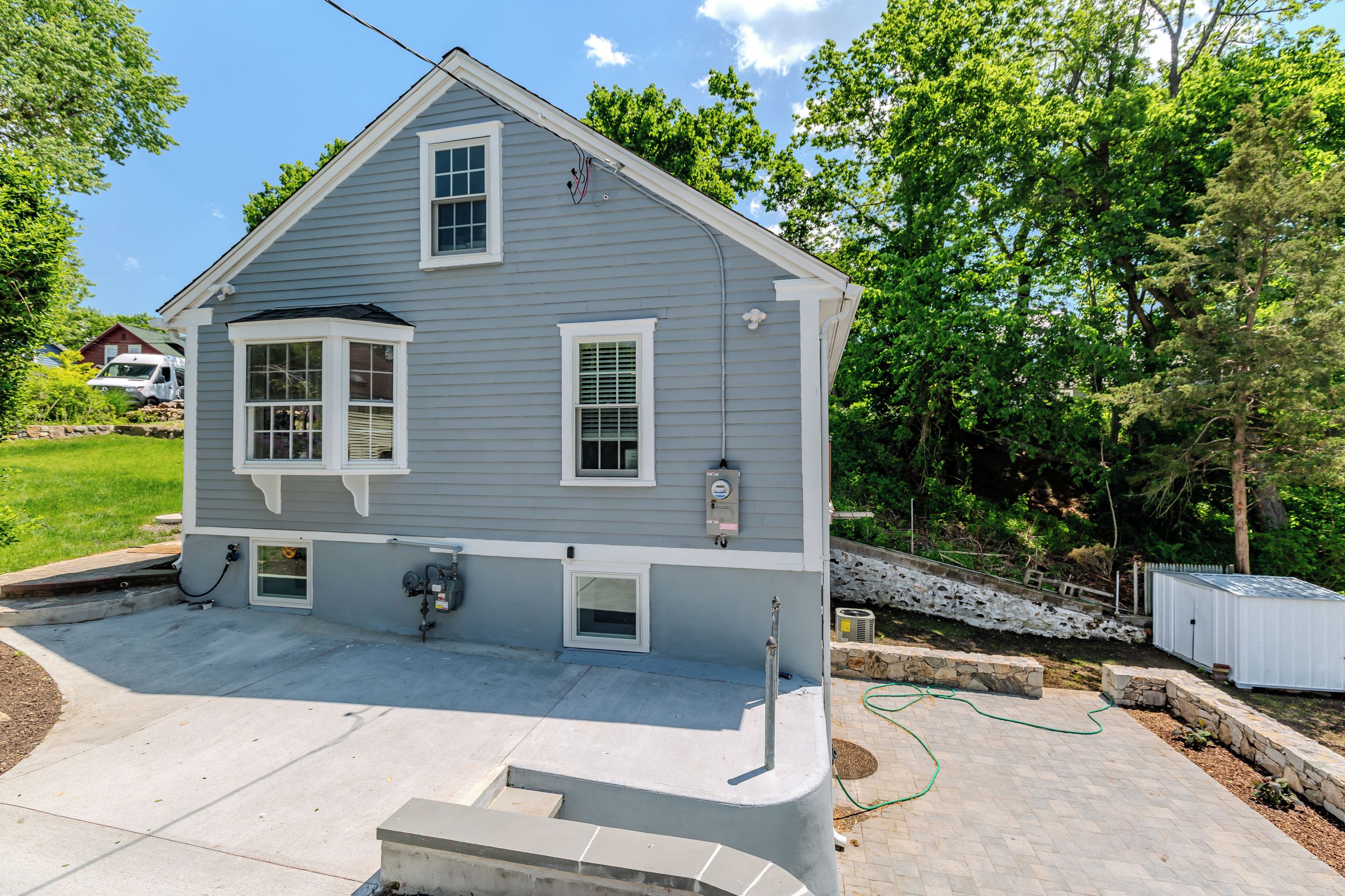 A two-story house with a front porch, a garage, and a small attached shed.