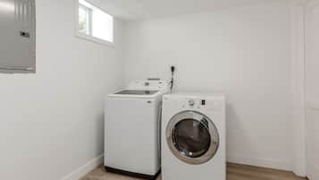 Une buanderie équipée d’un lave-linge et d’un sèche-linge, avec une fenêtre et une porte.