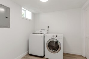 A laundry room with a washing machine and dryer, a window, and a door.