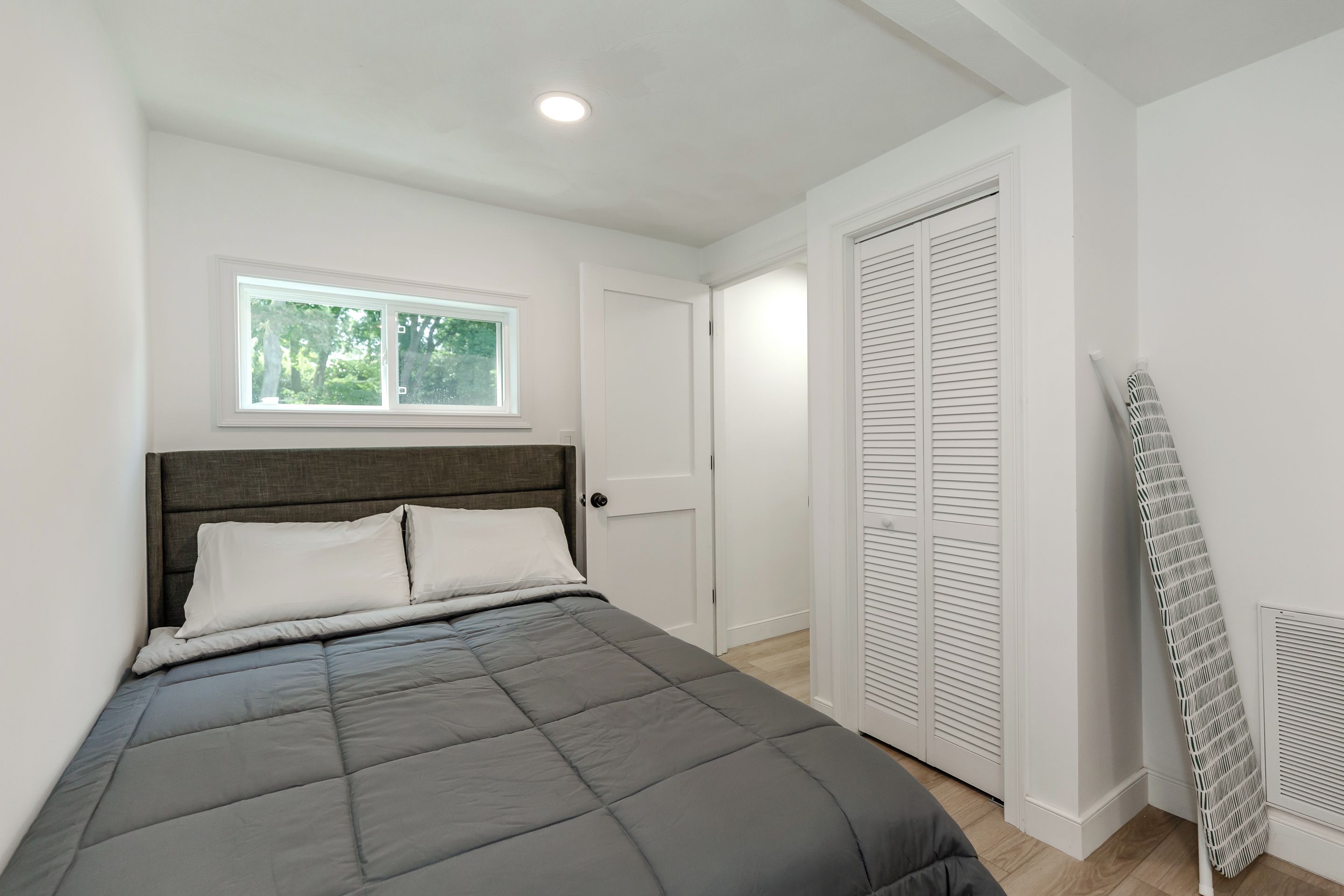 Ein Schlafzimmer mit Bett, Fenster, Tür und Heizkörper.