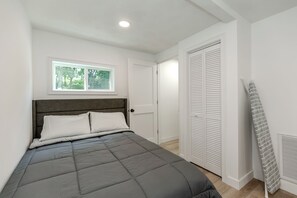 A bedroom with a bed, a window, a door, and a radiator.