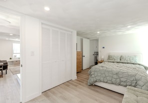 Un dormitorio moderno con una cama grande, un armario y un espacio de escritorio.