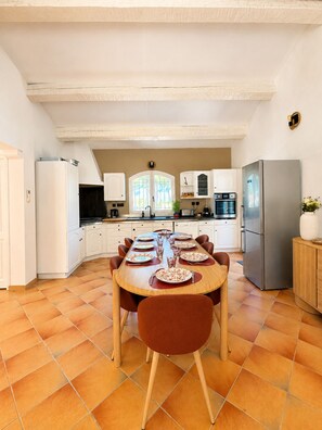 A modern kitchen with white cabinets, a stainless steel refrigerator, and a dining table set for six. - Villa Souleou - Giens Peninsula - Swimming Pool (Hyères)