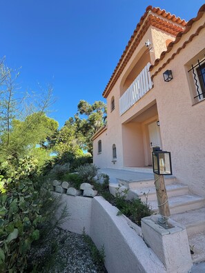 A two-story building with a balcony, a stone staircase, and a garden area. - Villa Souleou - Giens Peninsula - Swimming Pool (Hyères)
