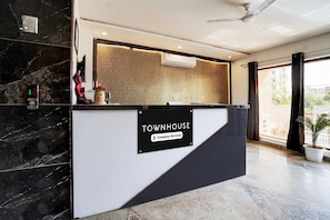 A reception desk with a sign reading 'TOWNHOUSE Company-Serviced' in a modern interior with marble flooring and a ceiling fan.