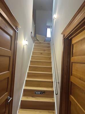 A wooden staircase with a handrail, flanked by wooden doors, leading to an upper floor. - My place of peace (Henfield)