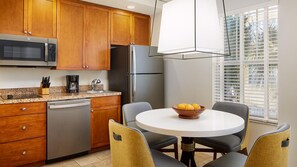 A modern kitchen with wooden cabinets, stainless steel appliances, and a round dining table with chairs. -  After the thrill of theme parks, you’ll enjoy endless at Sheraton Vistana (Orlando)