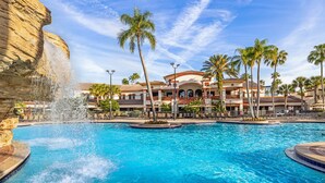 Ein Hotel mit großem Pool, Palmen und einem Wasserfall.
