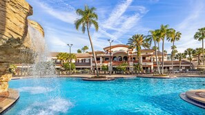 A hotel with a large pool, palm trees, and a waterfall feature. -  After the thrill of theme parks, you’ll enjoy endless at Sheraton Vistana (Orlando)