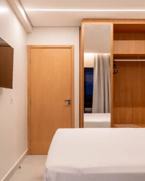 A hotel room with a bed, a wooden wardrobe, and a door. - Apartment in Salinas, Premium Hotel Resort (Salinópolis)