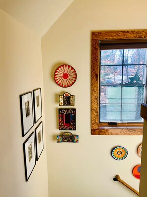 Una habitación con ventana, decoraciones en la pared y suelo de madera.