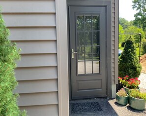 Puerta frontal de color oscuro con un panel de vidrio, un tirador metálico y un panel decorativo debajo de la puerta.
