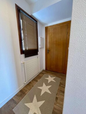 A hallway with a radiator, a wooden door, and a star-patterned rug. - 250m from ski lifts, 3rd floor, balcony, tv, 41m², Alpe d'Huez (L'Alpe d'Huez)