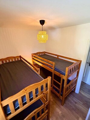 Quarto com duas camas beliche e luminária pendente.