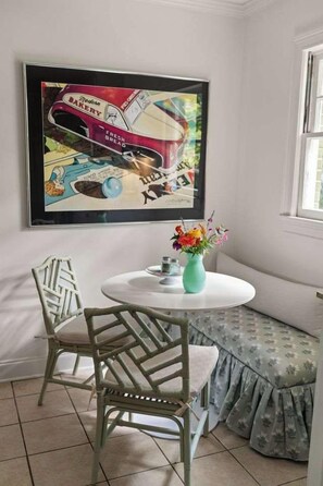 A room with a round table, two chairs, a bench, a framed artwork, and a vase with flowers. - The Sivley House (Oxford)