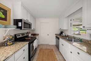 A kitchen with white cabinets, a microwave, stove, and a sink. - The Sivley House (Oxford)