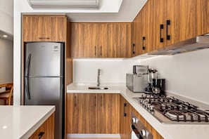 Eine moderne Küche mit Holzausstattung, einem Edelstahl-Kühlschrank, einem Gasherd und einem eingebauten Backofen.
