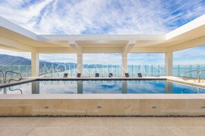 Ein Dachpool mit Infinity-Kante und freiem Blick auf Berge und Himmel.