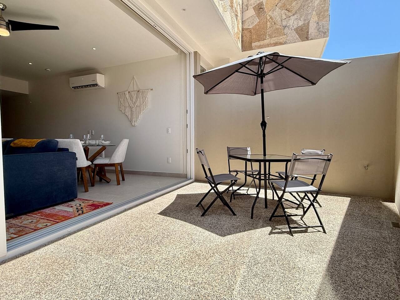 An outdoor patio with a table and chairs, a ceiling fan, and a large umbrella.