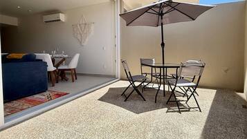 An outdoor patio with a table and chairs, a ceiling fan, and a large umbrella.