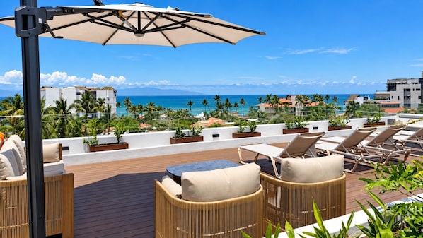 A rooftop terrace with lounge chairs, a table, and an umbrella. - Brand-New 1BR Retreat with Spacious Patio in Bucerías (Bucerías)