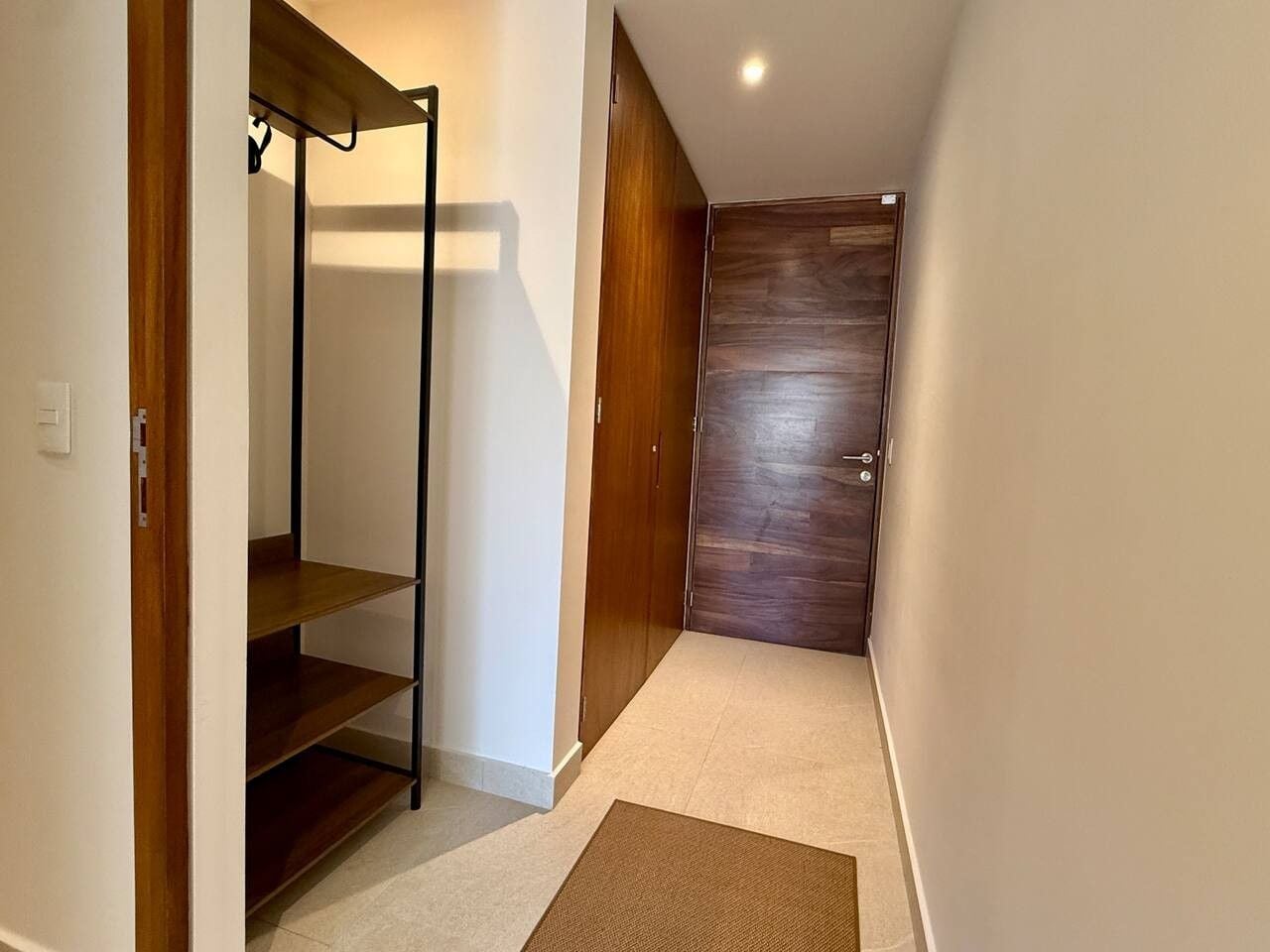 A hallway with a wooden wardrobe, a metal shelf unit, and a carpet.