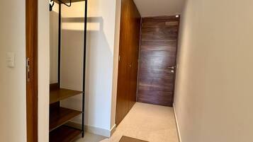 A hallway with a wooden wardrobe, a metal shelf unit, and a carpet.
