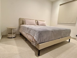 A bedroom with a bed, pillows, a bedside table, and a wall-mounted light fixture. - Brand-New 1BR Retreat with Spacious Patio in Bucerías (Bucerías)