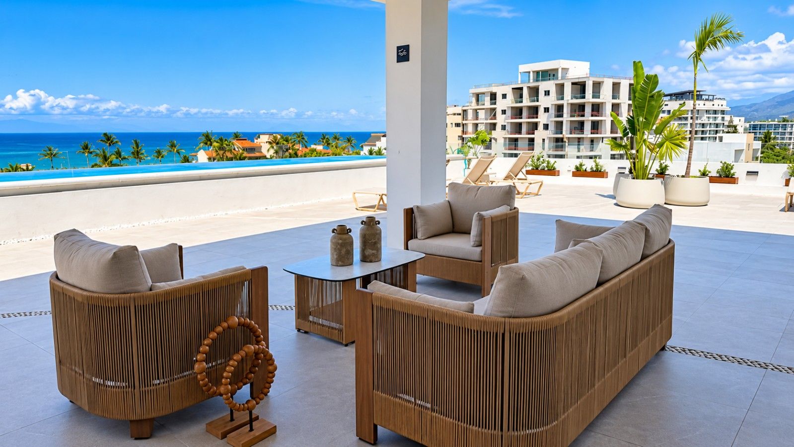 A rooftop lounge with a view of the ocean and a building in the background.