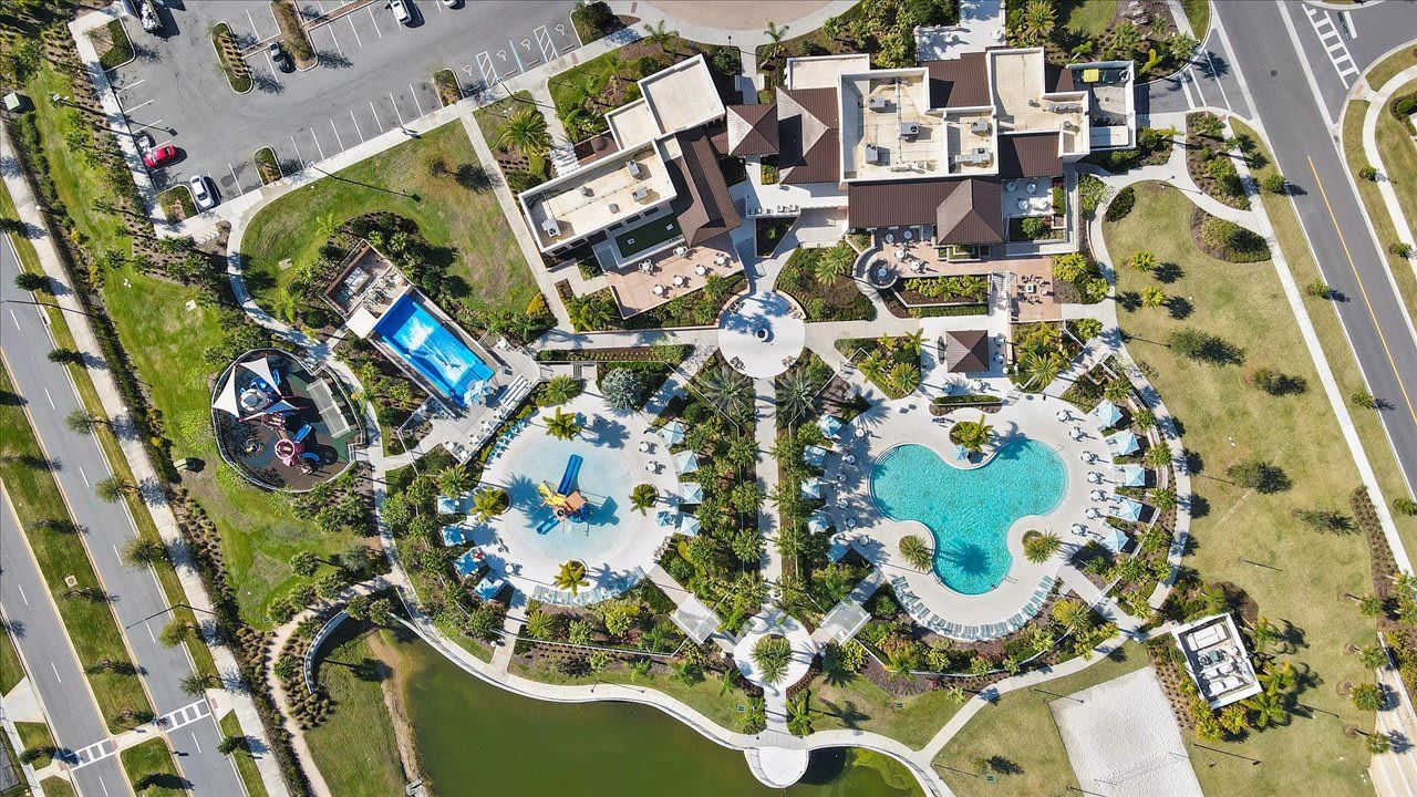 Luchtbeeld van een resort met meerdere zwembaden, een golfbaan en een ruime parkeerplaats.