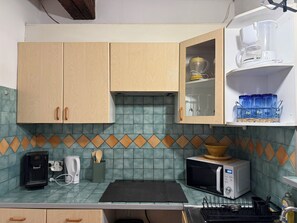 A kitchen with wooden cabinets, a microwave, a coffee maker, and a water dispenser. - PERPIGNAN STUDIO CENTER (Perpignan)