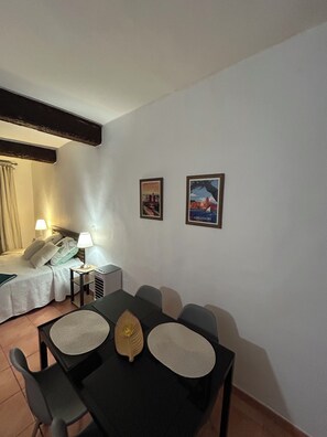 A hotel room with a bed, bedside lamps, a table with chairs, and two framed pictures on the wall. - PERPIGNAN STUDIO CENTER (Perpignan)