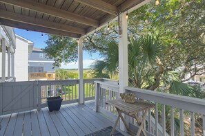 A covered outdoor deck with a railing, a wooden table, and a potted plant. - A Beach Escape | Ocean Balcony, Bunk Room, Dogs OK (North Topsail Beach)