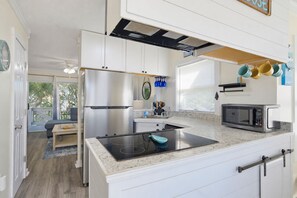 A compact kitchen with a built-in refrigerator, microwave, and stove. - A Beach Escape | Ocean Balcony, Bunk Room, Dogs OK (North Topsail Beach)