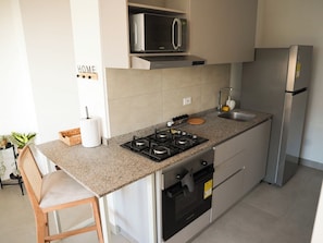 Eine kompakte Küche mit Gasherd, Mikrowelle und Edelstahl-Kühlschrank.